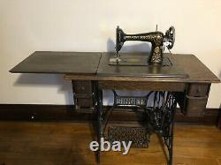 1910 vintage Singer Red Eye sewing machine with oak cabinet. Has belt and works