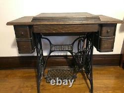 1910 vintage Singer Red Eye sewing machine with oak cabinet. Has belt and works