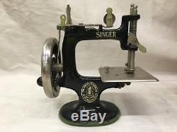 Antique child's singer sewing machine with doll mannequin