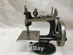 Antique child's singer sewing machine with doll mannequin