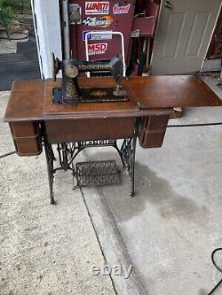 Machine à coudre à pédale Singer antique de 1919 dans un meuble en bois modèle Red Eye 66.